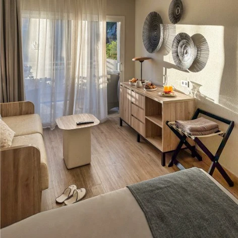 Interior luminoso con cama, muebles de madera, ventanal y decoraci&oacute;n pared