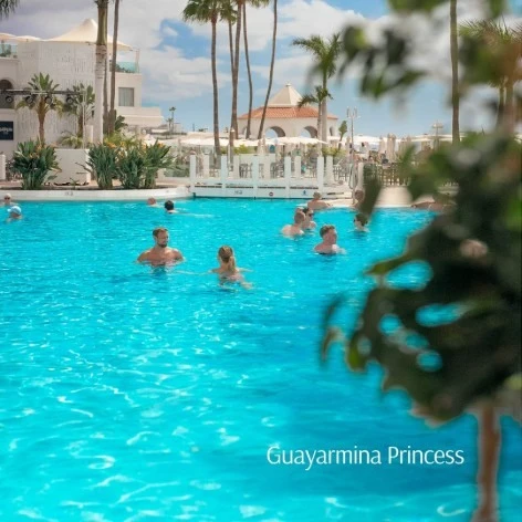 Piscina tropical con ba&ntilde;istas y palmeras en el hotel Guayarmina Princess.