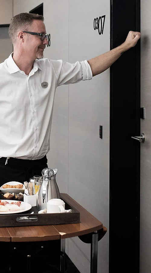 Hombre con uniforme blanco se&ntilde;ala la puerta negra con el n&uacute;mero 087