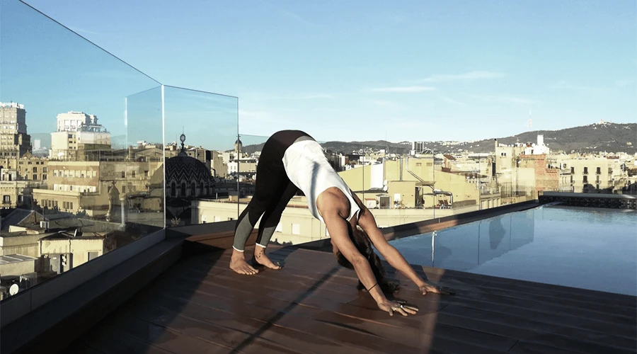 Dos personas haciendo yoga en una azotea con vista a la ciudad
