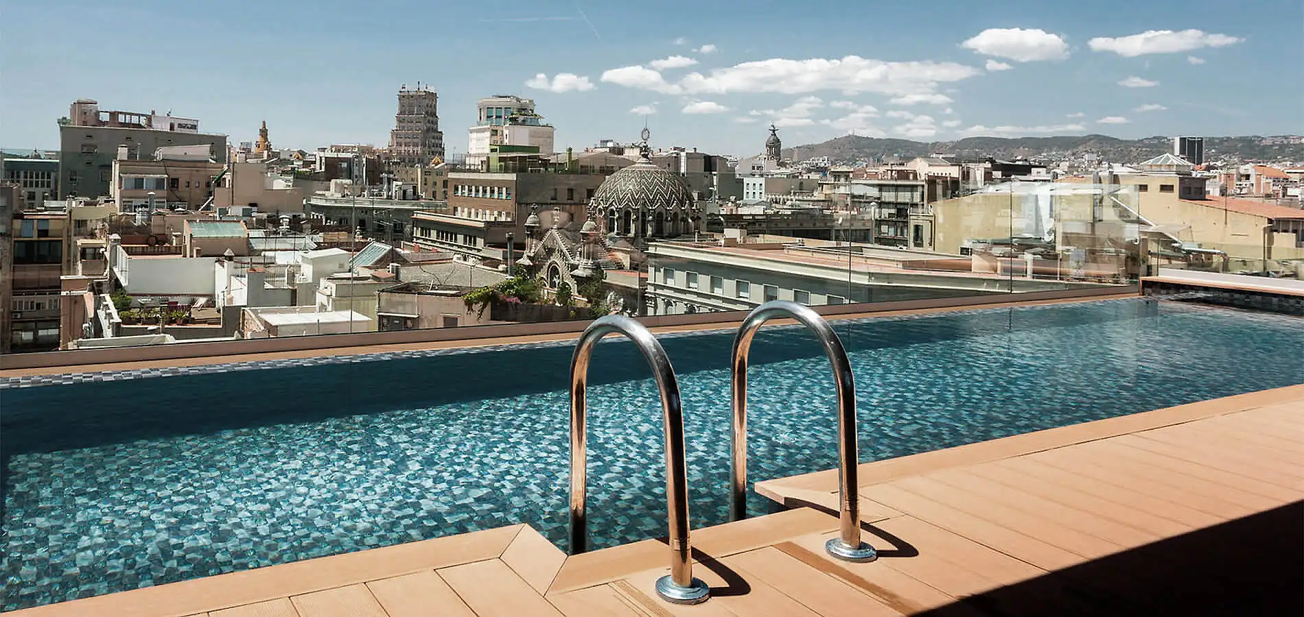 Vista urbana desde una piscina; tejados y catedral al fondo, cielo nublado