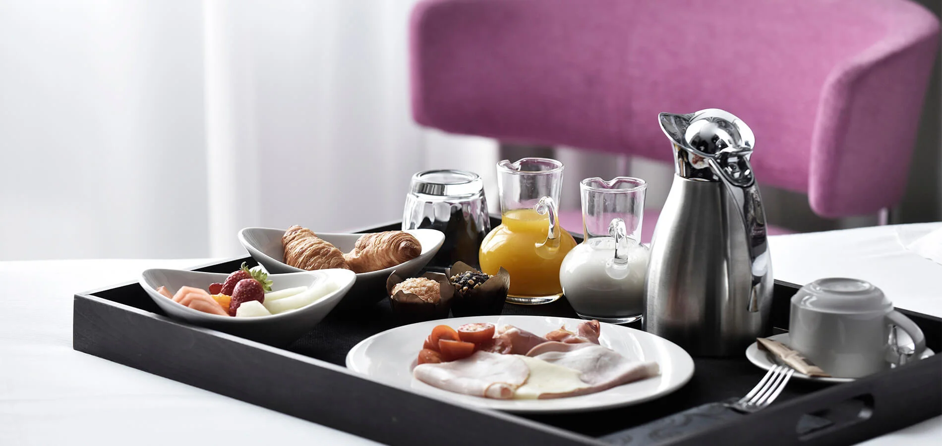 Desayuno con t&eacute; y platos en bandeja, junto a silla morada.