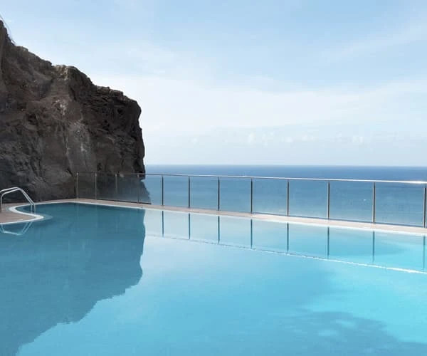 Piscina infinita con vista al mar y acantilado al atardecer