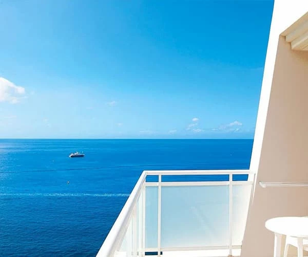Balc&oacute;n con vista al mar azul y un barco en el horizonte