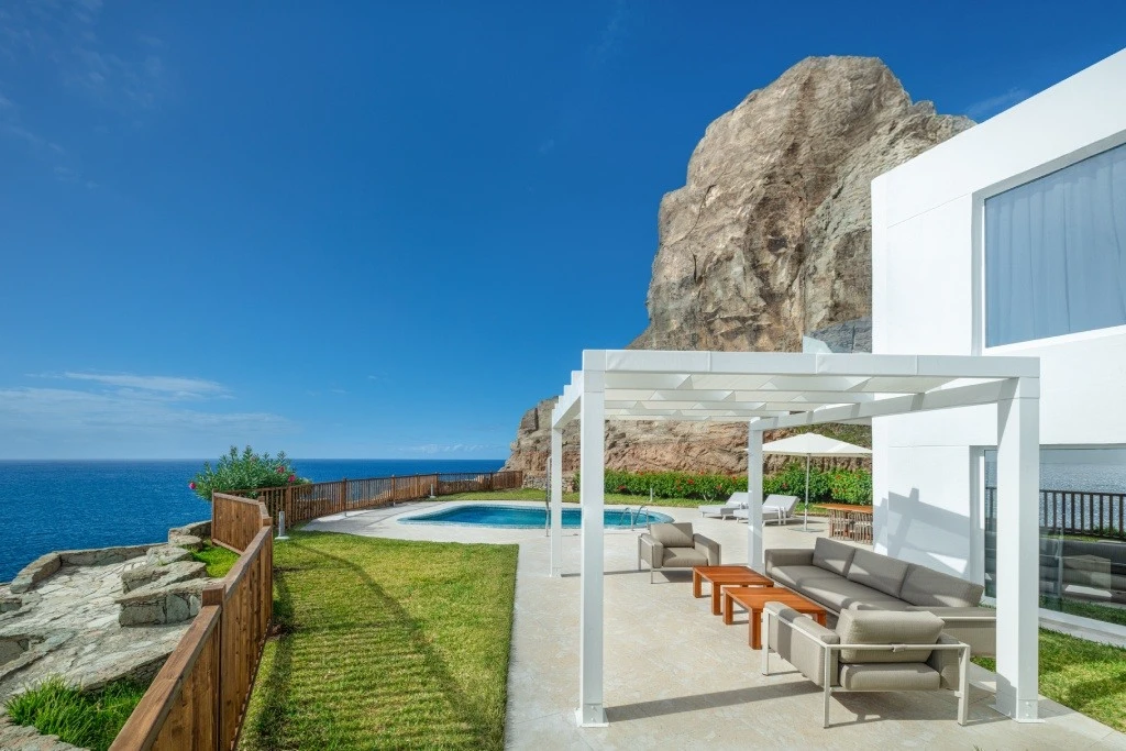 Terraza con piscina y tumbonas junto al mar, bajo cielo despejado