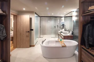Ba&ntilde;o moderno con ba&ntilde;era blanca, ducha de vidrio y lavamanos de madera