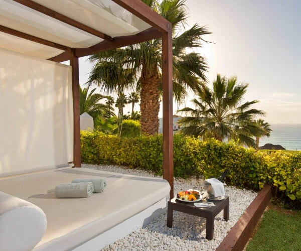 Terraza con cama, palmeras y vista al mar desde un alojamiento tropical