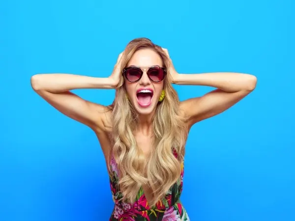 Mujer joven sonriente con gafas y vestido colorido sobre fondo azul