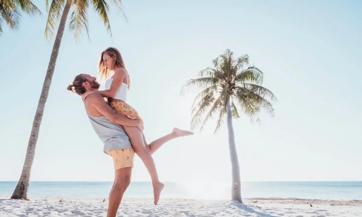 Mujer y ni&ntilde;a al aire libre en la playa con palmeras y salto juntos