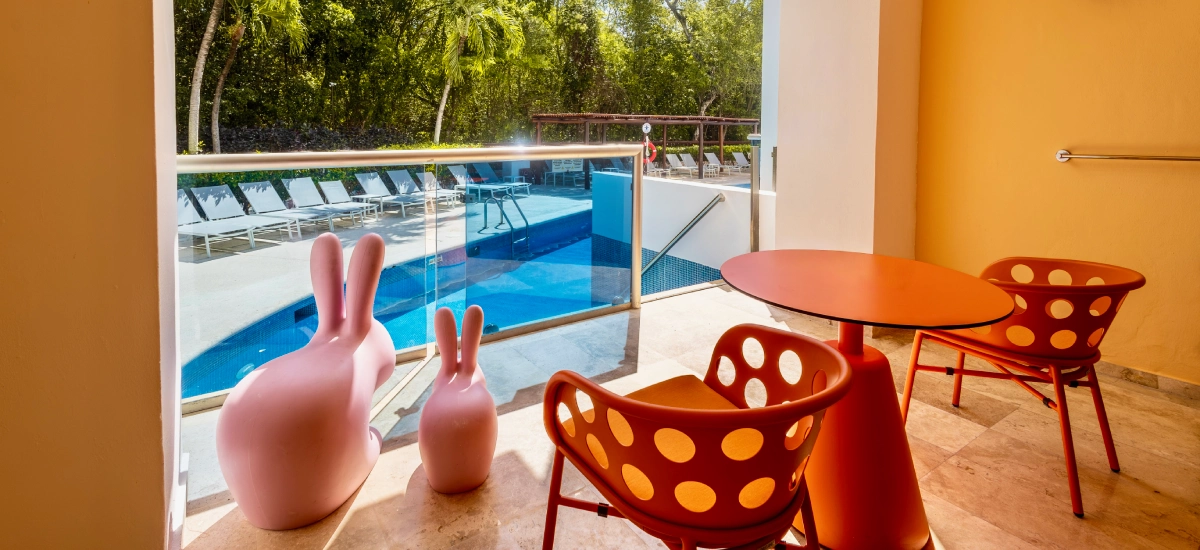 Terraza junto a piscina con sillas infantiles rojas y mesa naranja