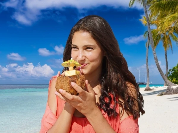 Mujer sonriente en playa tropical con coco y palmeras al fondo