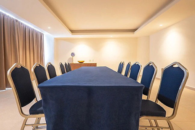 Sala de reuniones con mesa azul y sillas acolchadas, paredes beige.