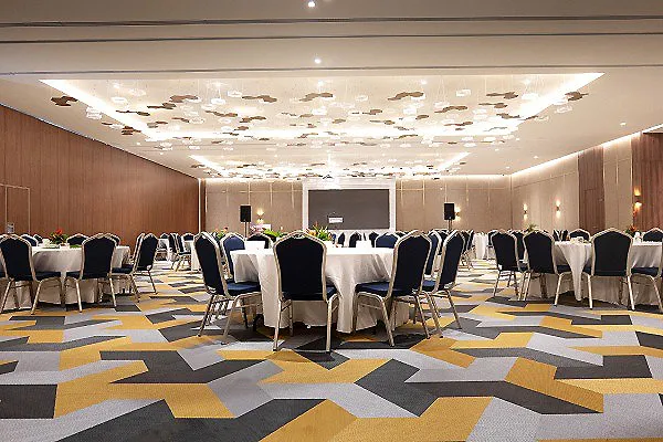Sala de conferencias con mesas y sillas, piso ajedrezado y luces LED.