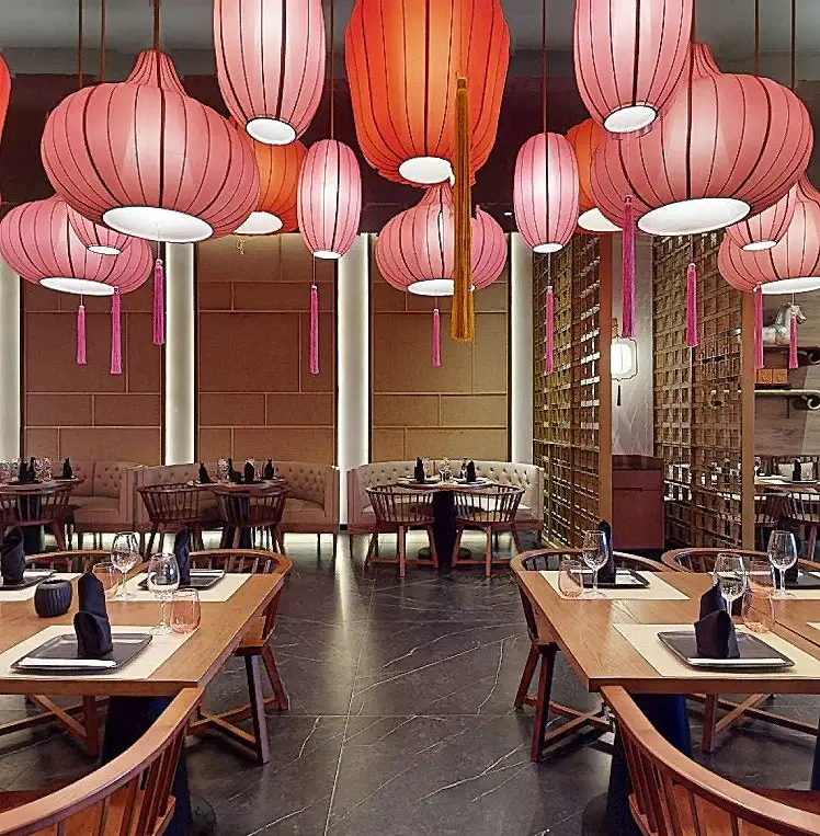 Sala de restaurante con mesas y l&aacute;mparas colgantes de faroles rosa.