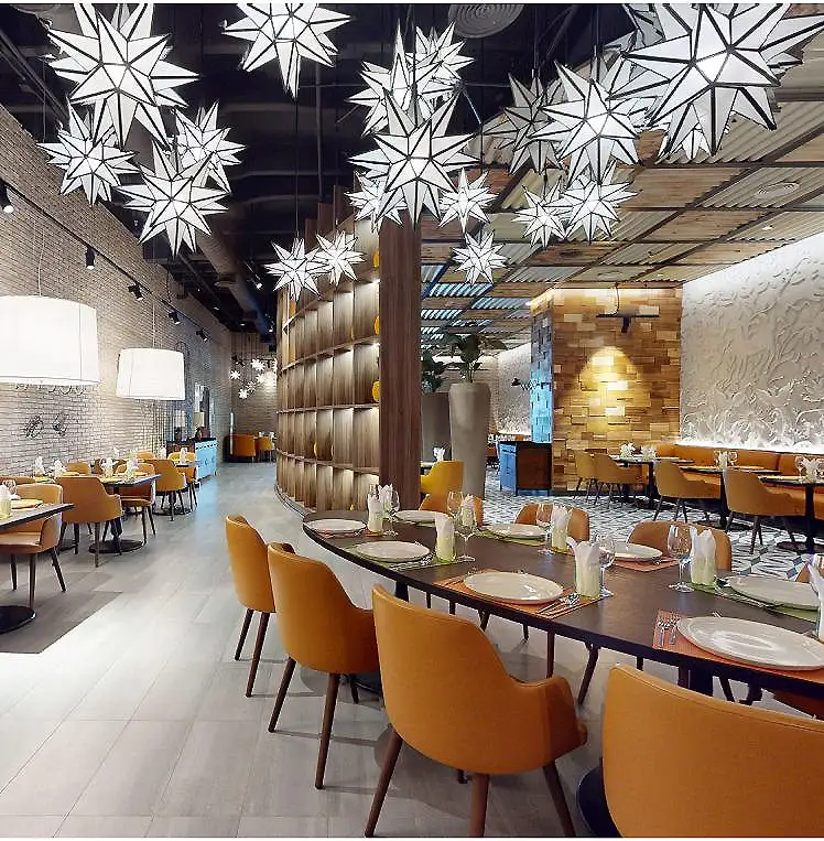 Restaurante con mesas y sillas, decoradas con grandes l&aacute;mparas de papel en forma de estrellas