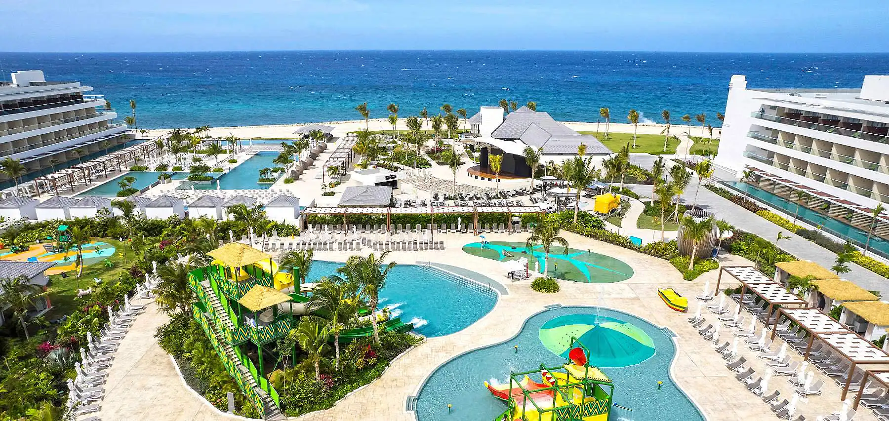 Vistas panor&aacute;micas de hotel junto al mar con piscinas y palmeras tropicales