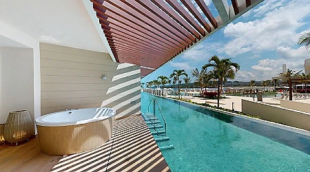 Piscina con jacuzzi al aire libre junto a palmeras y cielo azul