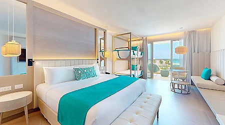 Habitaci&oacute;n de hotel moderna con cama doble y balc&oacute;n al mar.