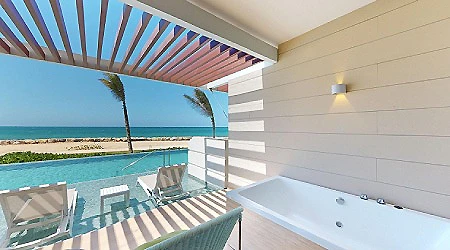 Terraza junto a piscina con vista al mar y jacuzzi en hotel.