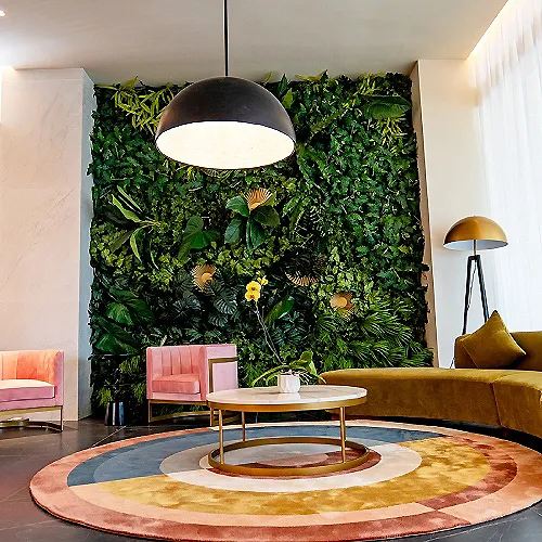 Muro verde decorativo con plantas, l&aacute;mpara y sala moderna con alfombra circular