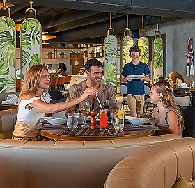 Personas brindando en un bar con camarero sirviendo bebidas y c&oacute;cteles
