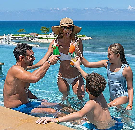 Familia jugando en la piscina, ni&ntilde;o salpicando a una mujer en traje de ba&ntilde;o.