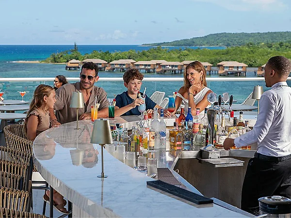 Grupo de amigos brindando en la barra con vista al mar y caba&ntilde;as