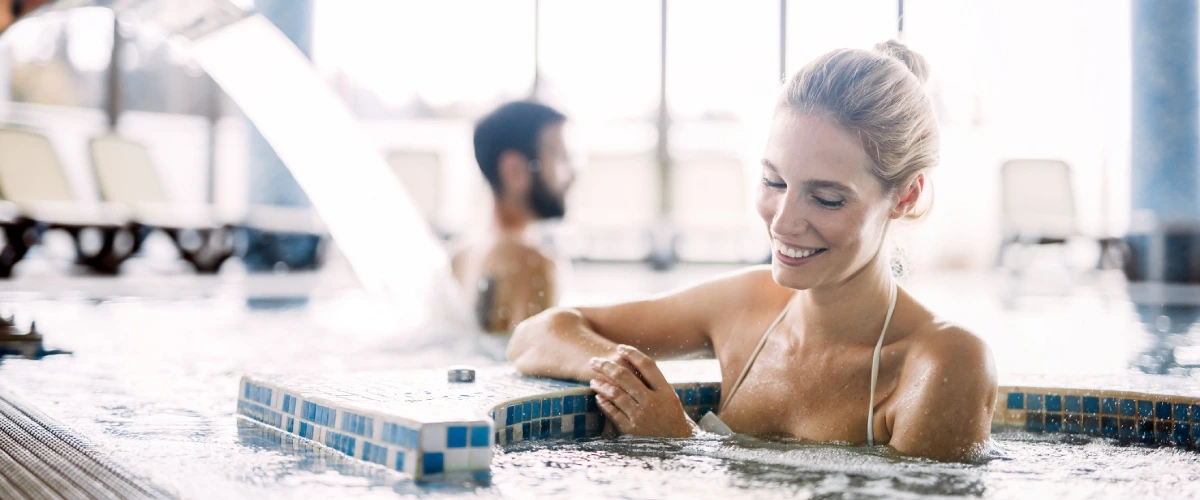 Mujer sonriente nadando en una piscina climatizada bajo techo.