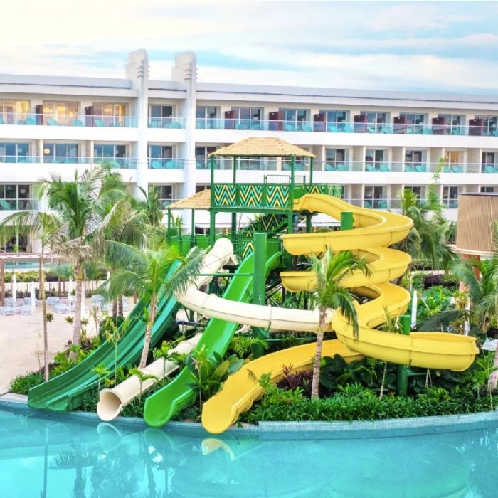 Hotel con toboganes acu&aacute;ticos verdes y amarillos frente a un edificio