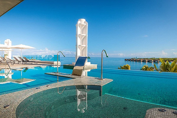 Piscina infinita con vista al mar y muelle al fondo