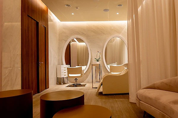 Interior de hotel con sof&aacute; beige, sill&oacute;n y espejos redondos al fondo
