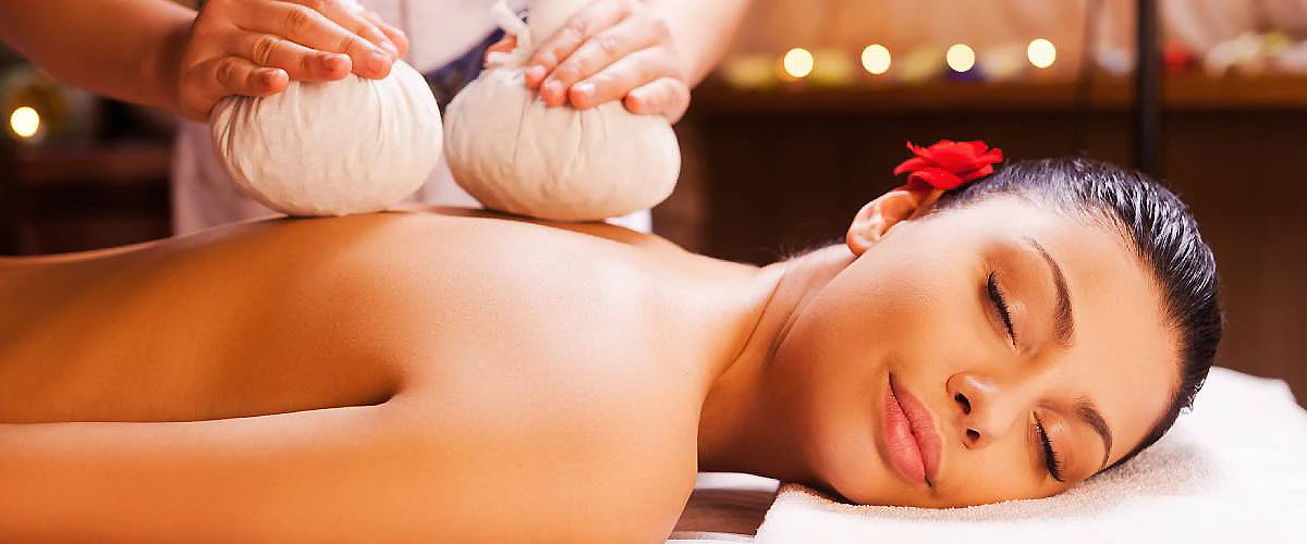 Masajista masajea a una mujer en un spa, con aroma y luz c&aacute;lida.