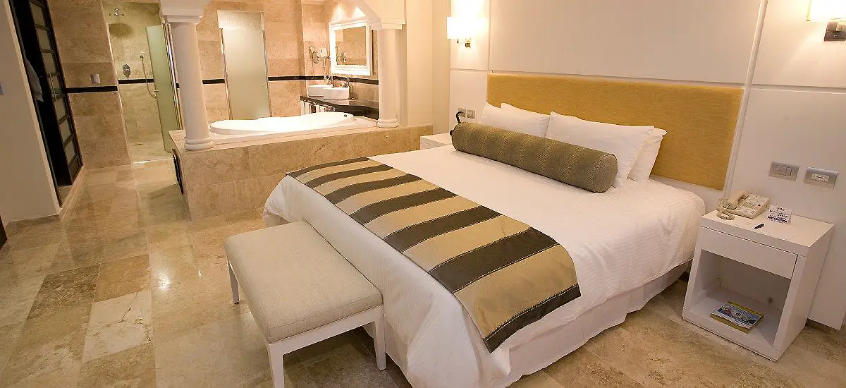 Dormitorio moderno con cama doble, mesita y ba&ntilde;o en suite al fondo.