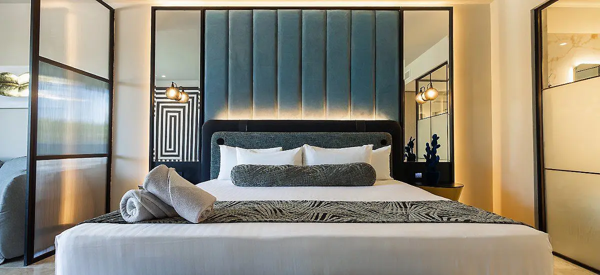 Dormitorio moderno con cama, cortinas azules y l&aacute;mparas de pared.