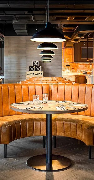 Mesa y sillas de terciopelo en un restaurante con l&aacute;mpara colgante y barra