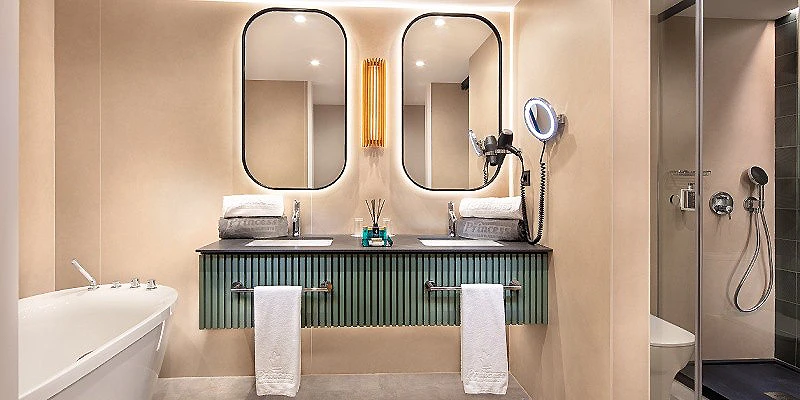 Lavabo doble con espejos ovalados, ba&ntilde;era y ducha en ba&ntilde;o moderno beige