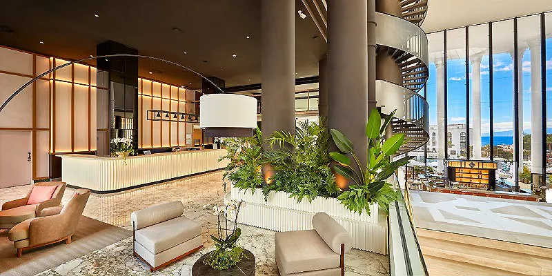 Lobby moderno con plantas y ventanales frente al mar