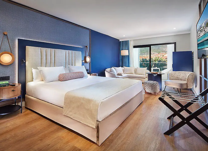 Dormitorio moderno con cama king, sill&oacute;n, ventana y decoraci&oacute;n azul y blanca.