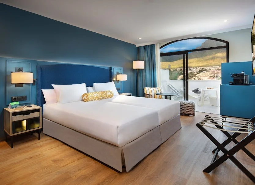 Habitaci&oacute;n de hotel moderna con cama doble y vista a paisaje desde ventana