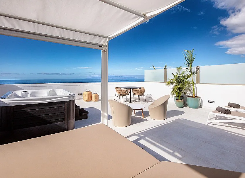 Terraza con jacuzzi, mesas y vista al mar bajo un cielo despejado