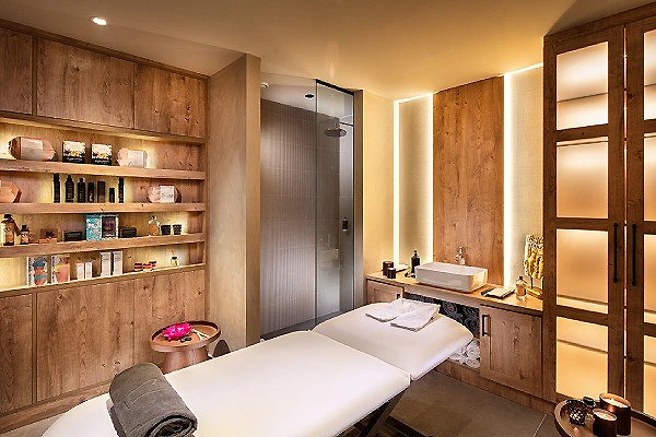 Sala de masaje con camilla blanca y muebles de madera en spa moderno
