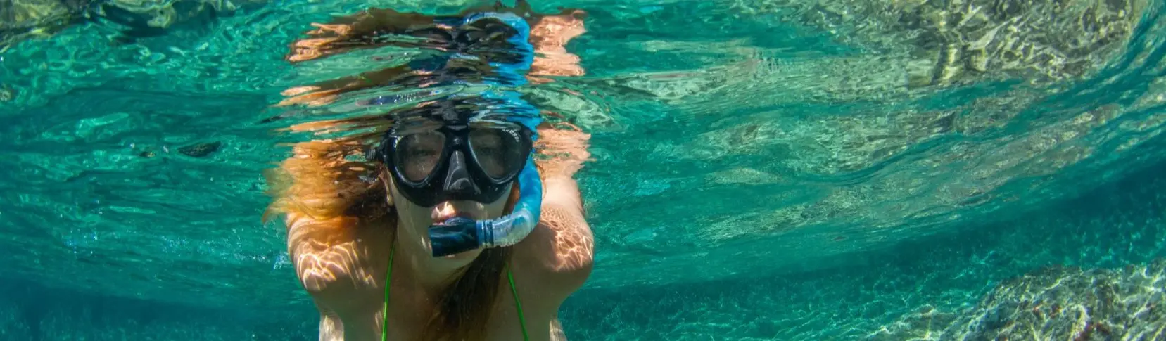 Persona nadando con gafas y snorkel en el mar, bajo el agua
