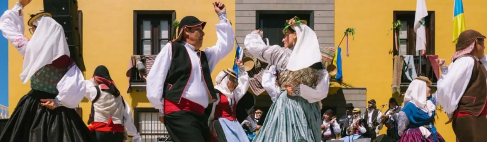 Baile tradicional con m&uacute;sicos y parejas levantando los brazos en la calle.