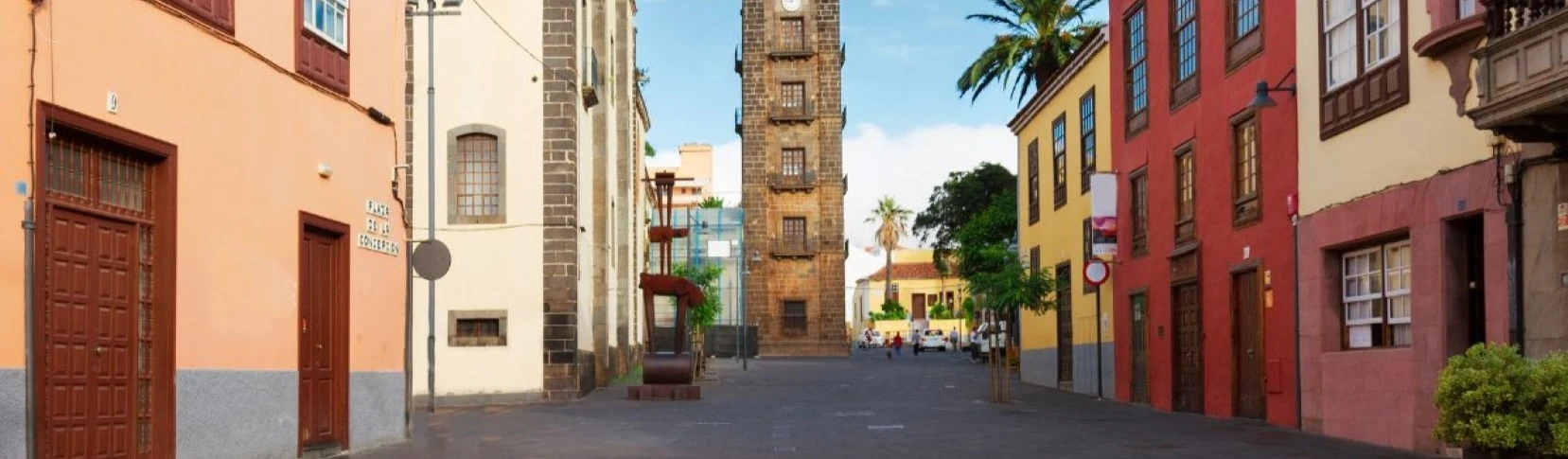 Calle empedrada con edificios de colores y torre central en Las Palmas