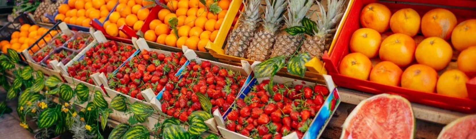 Cajas de naranjas, pi&ntilde;a y fresas en un mercado al aire libre