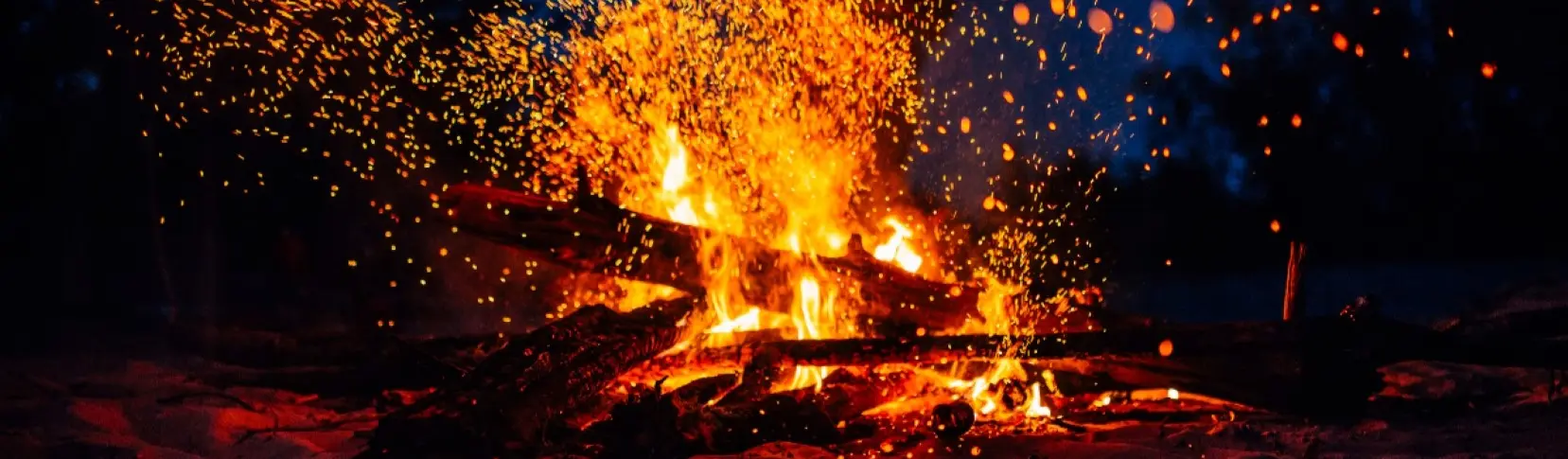 Fuego y chispas explosivas sobre una fogata encendida en la noche