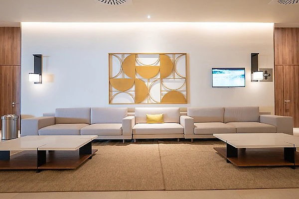Sala de estar moderna con sof&aacute;s beige, mesas bajas y cuadro decorativo.