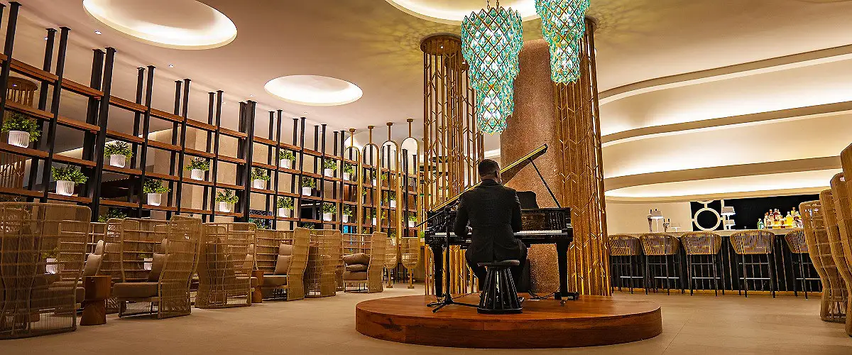 Interior de evento con piano y sillas, y escenario con decoraci&oacute;n azul dorada