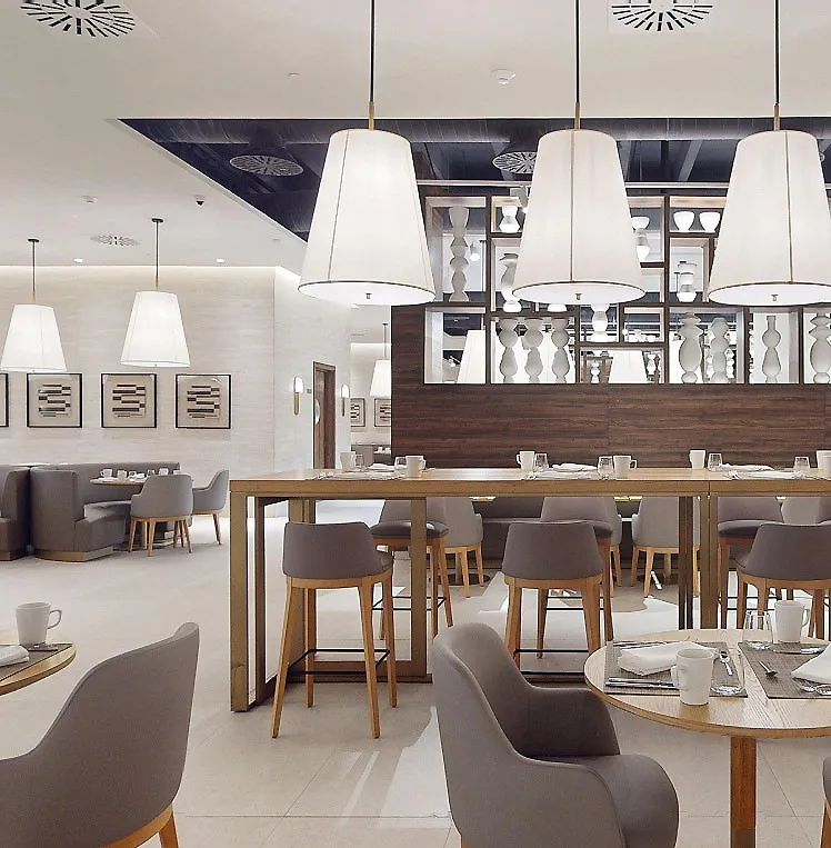 Interior de un restaurante moderno con mesas, sillas y l&aacute;mparas colgantes