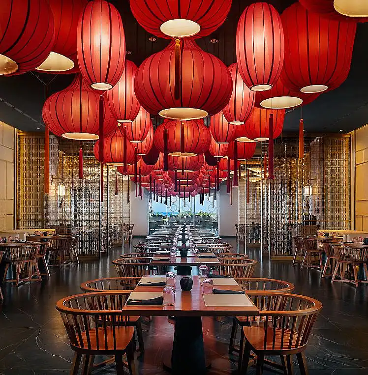Sal&oacute;n con faroles rojos colgantes y mesas redondas en un restaurante oriental